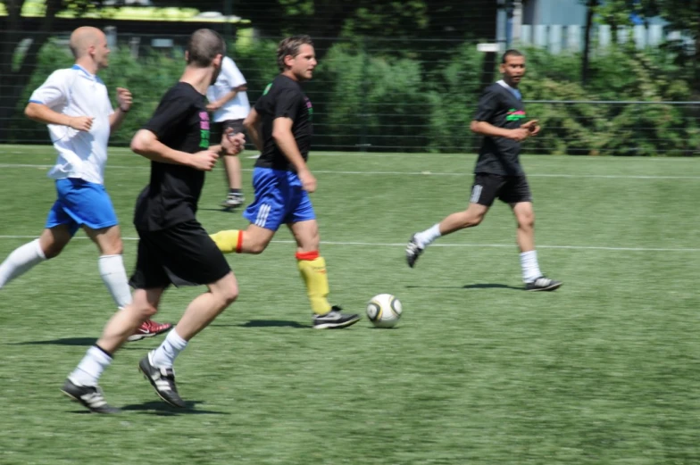 men in action on a soccer field, one is running after the ball