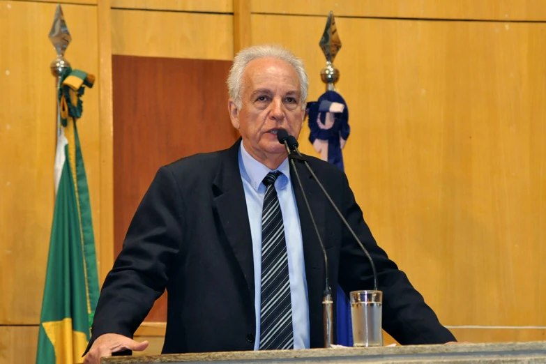 an older gentleman wearing a suit and tie standing behind a podium