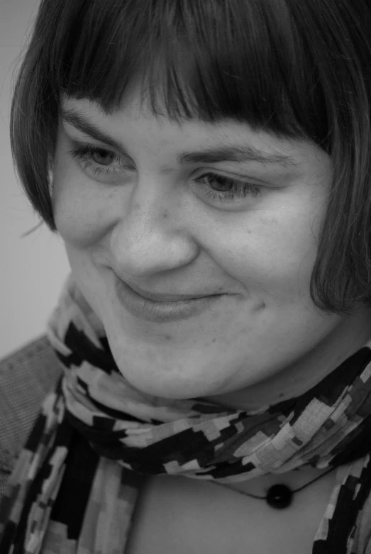 a woman smiling at the camera wearing a scarf