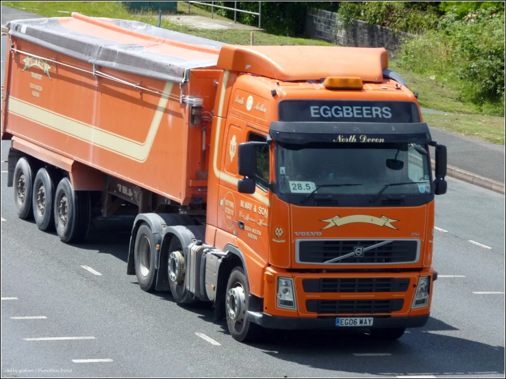 an orange tractor trailer hauling supplies on the road