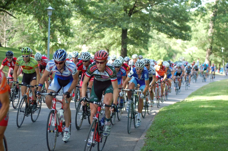 a bunch of bicyclists ride down the road together