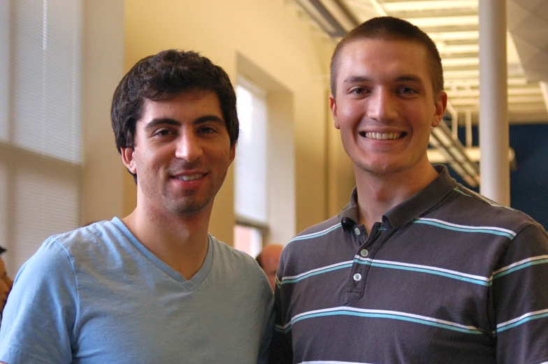 two young men standing next to each other smiling