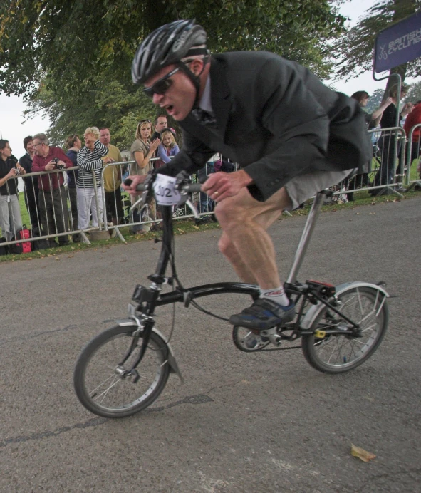 man riding bicycle down road while onlookers watch