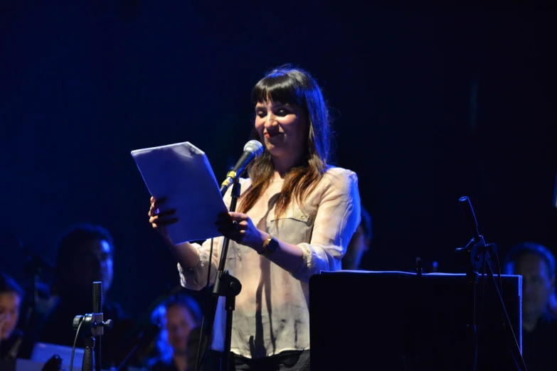 woman holding a microphone and standing on stage at an event