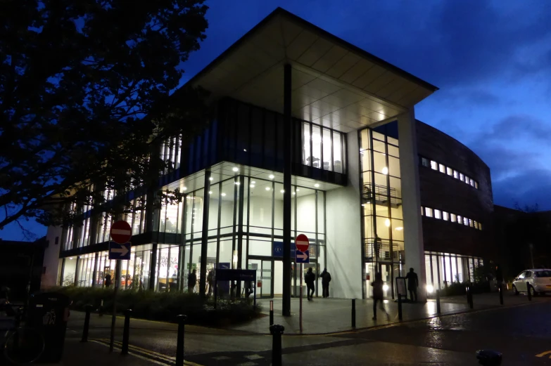 a modern building at night with people and cars