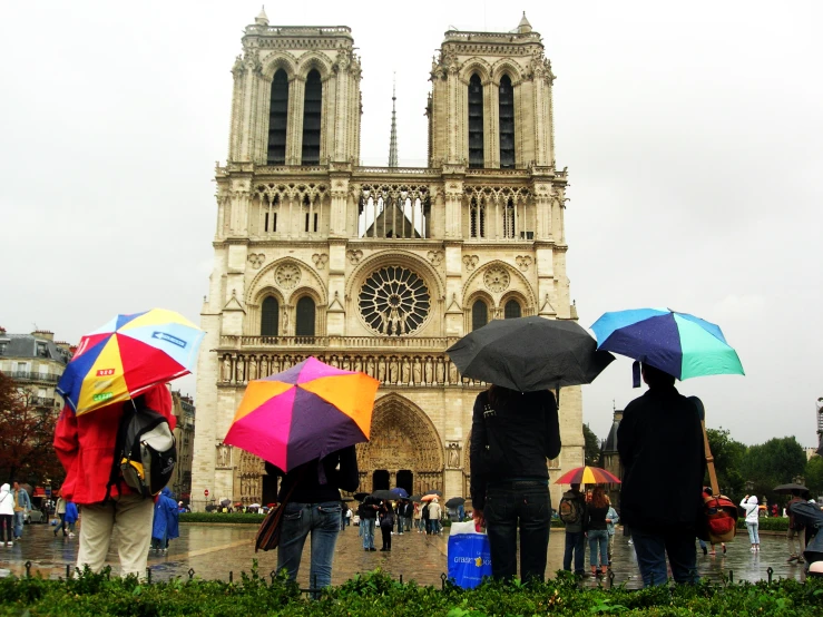 people stand in the rain in front of the cathedral