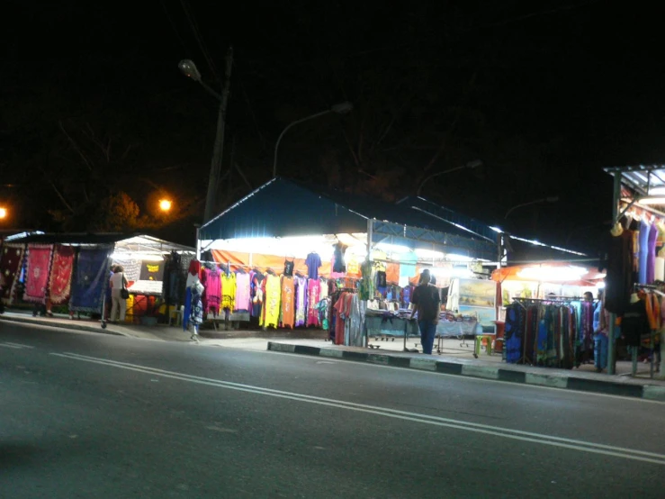 a street with several booths selling clothing at night