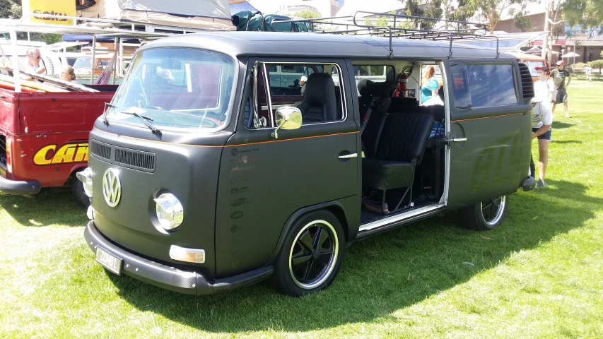 an old vw bus with some people looking at it