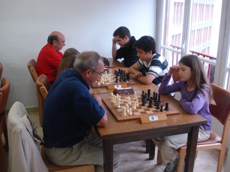 an elderly man sitting at a table with a  playing chess