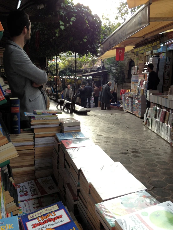 a woman sits at a bookshop in front of several stacked books