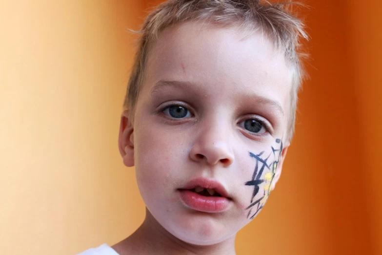 the young child has black and white markings on his face