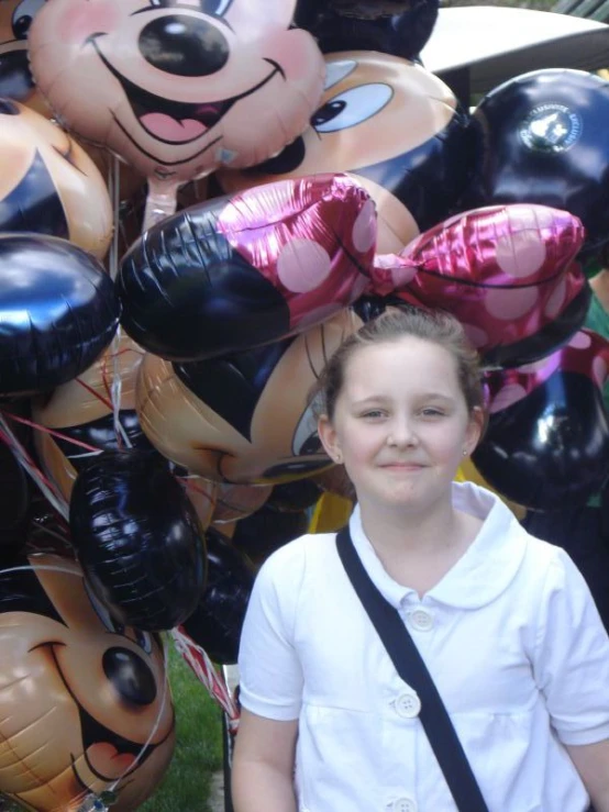 the girl is standing in front of balloons with minnie mouse heads