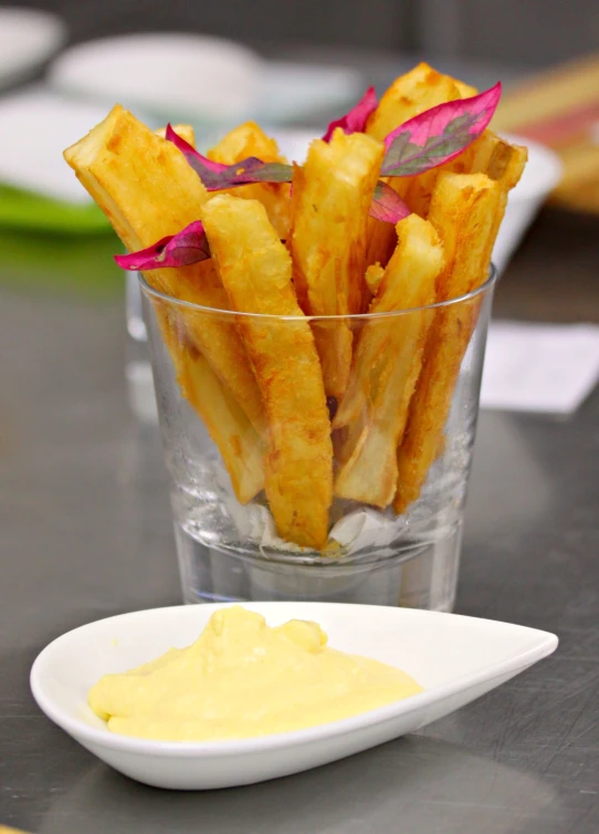 a glass of french fries and mayo on a table