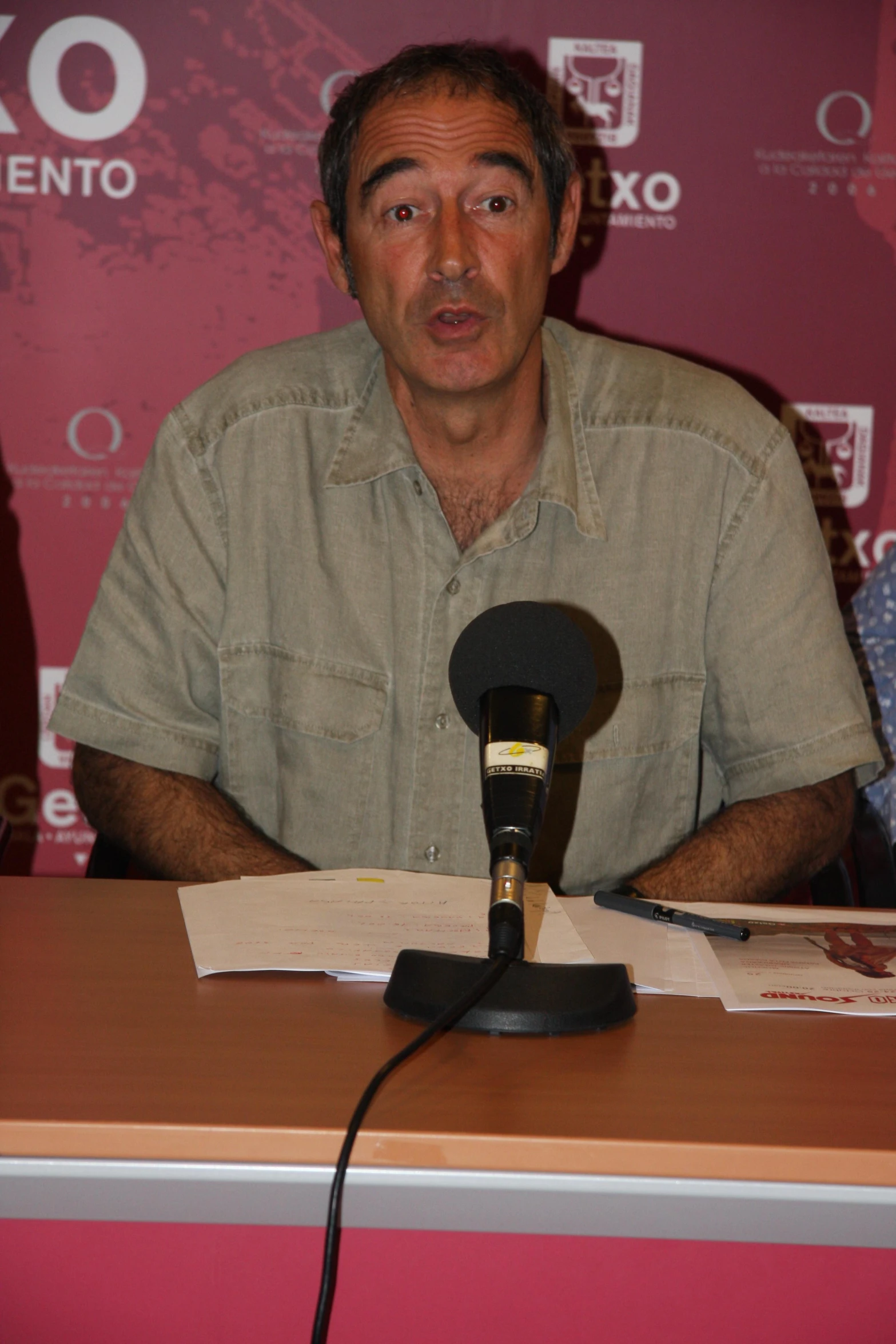 an older man sitting in front of a microphone