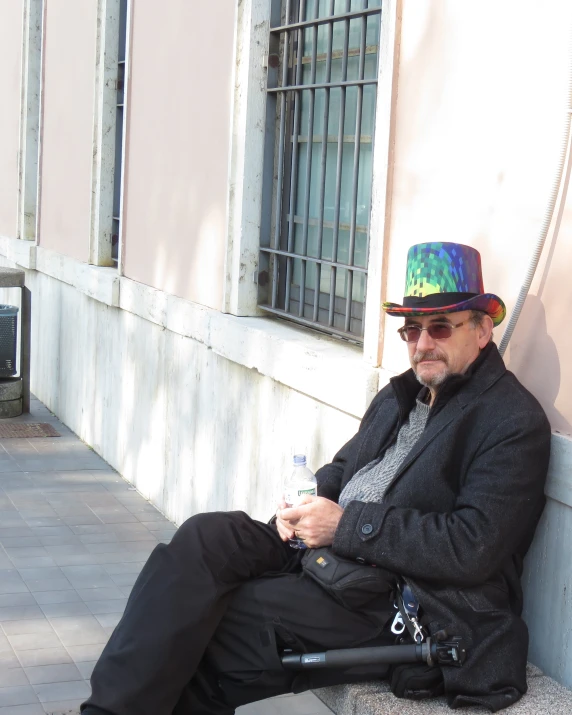 a man wearing a hat and jacket sitting on a bench