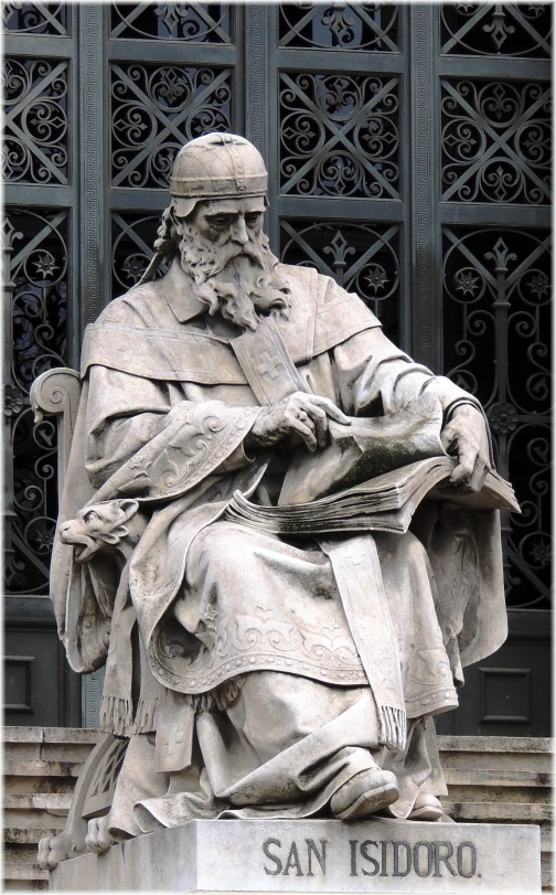 the statue in front of an iron gate with a beard and large hat