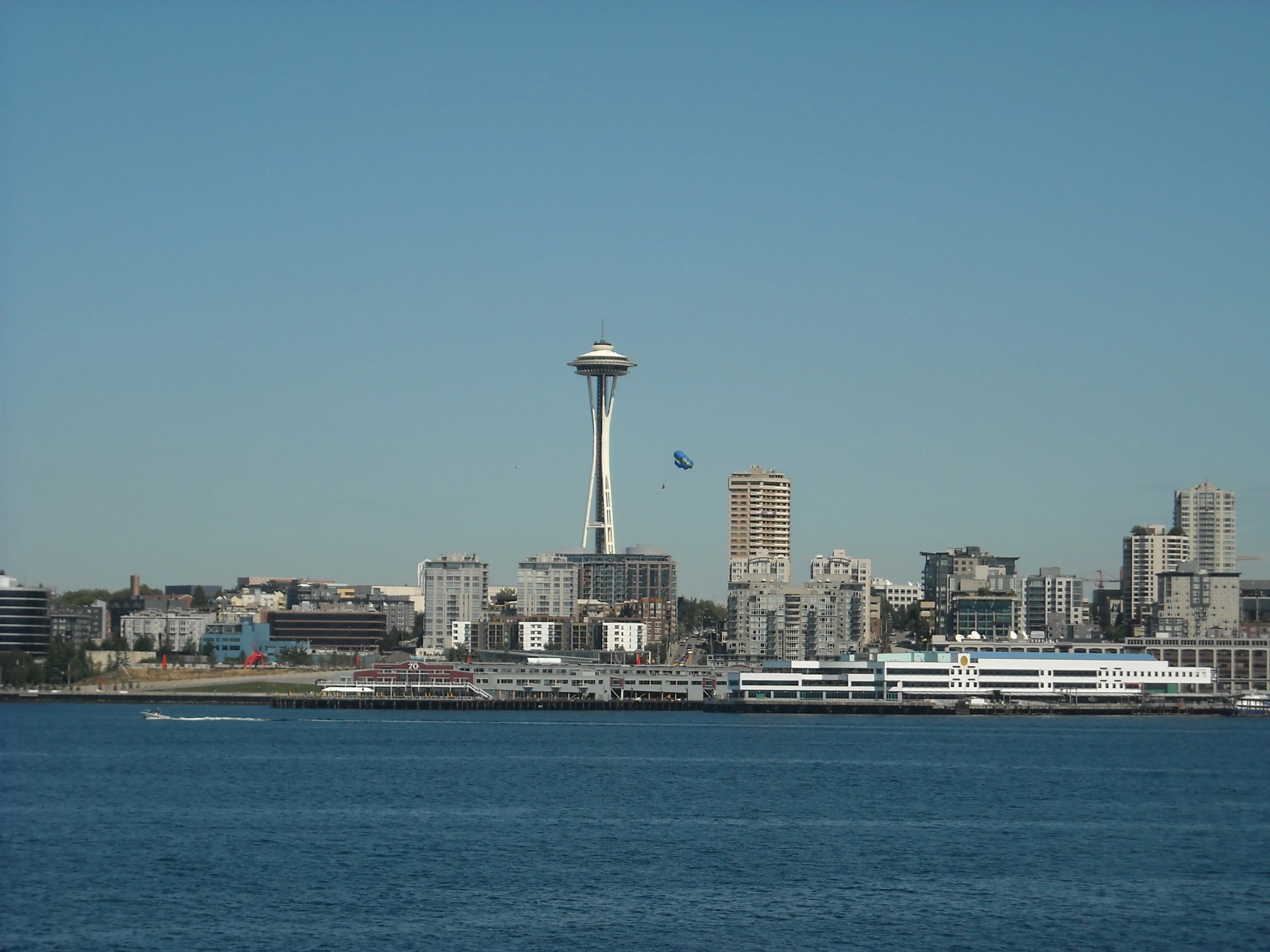 an air plane flying in front of the ocean with a city view