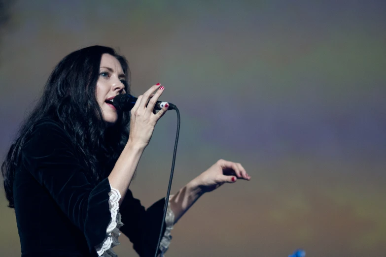 a woman sings into a microphone while holding her hands out