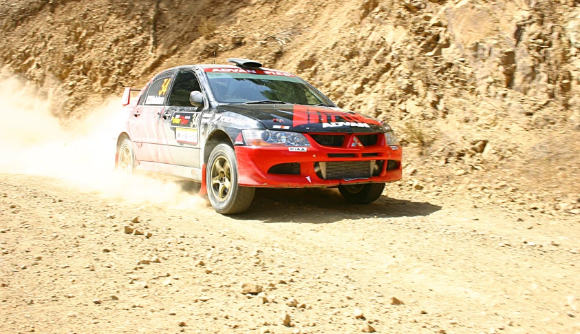 a red and black car driving down a dirt road