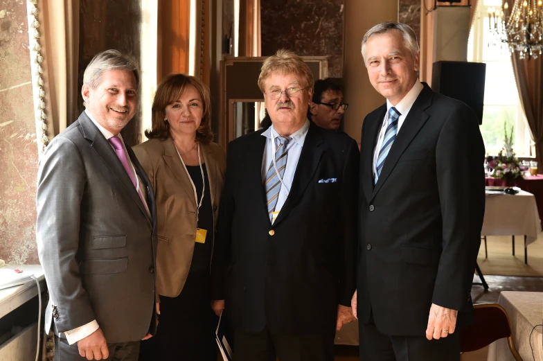 three men and one woman smiling together at a formal event