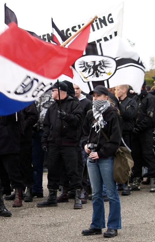 protesters stand in a protest, one has her face close to the camera and wearing masks