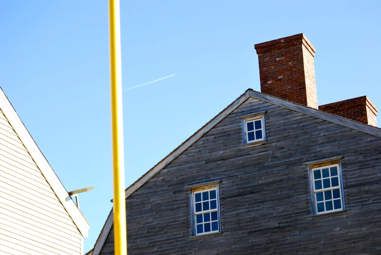 a tall building with a brick chimney next to a yellow pole
