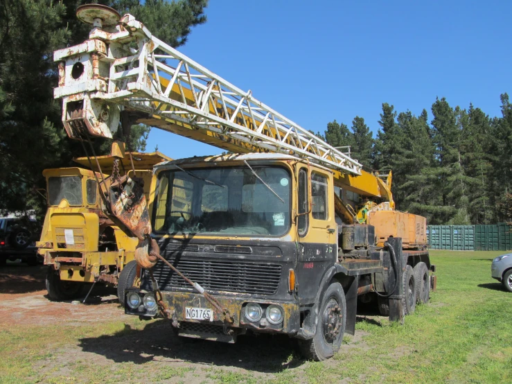 a truck parked in the grass with a construction crane on top