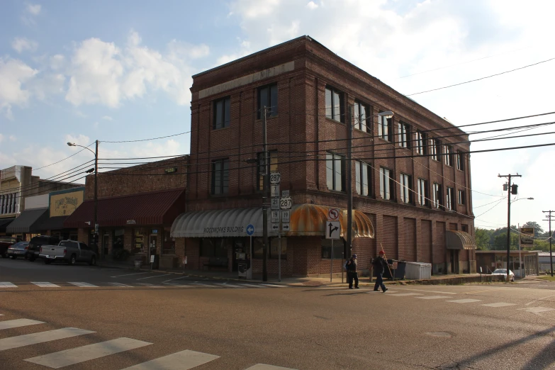 an old brick building is across the street from people