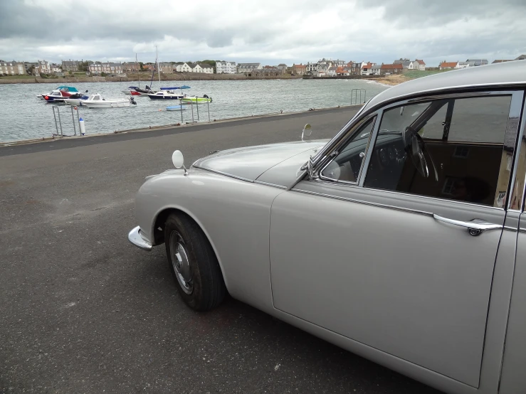 old fashioned car with a few boats in the bay