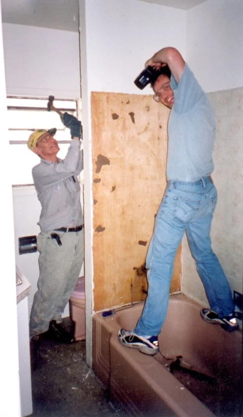 two men using a drill gun to remove wooden paneling