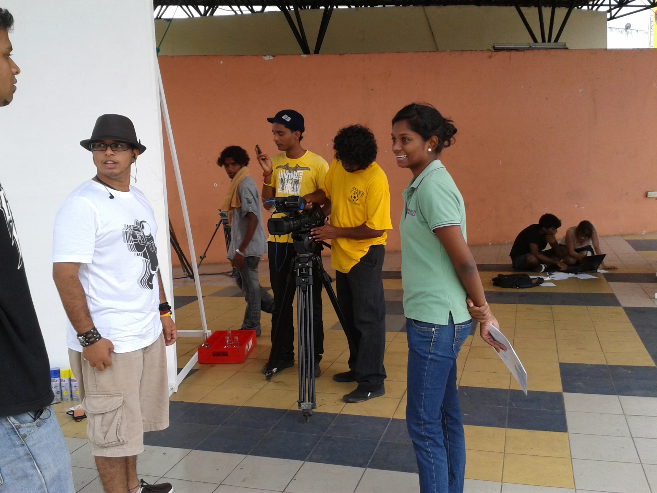 a group of people gathered in a room with a yellow brick wall