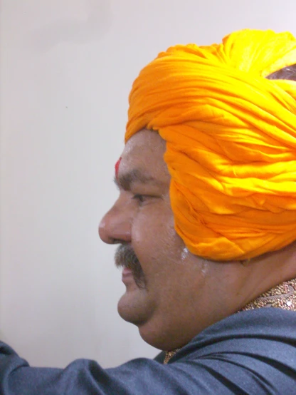 a man in an orange turban holding his hair