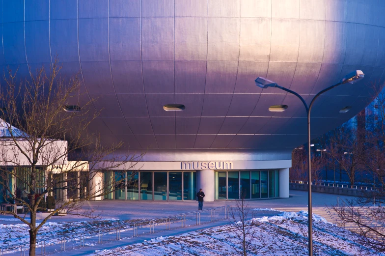 a large circular metal building with a tall lamppost