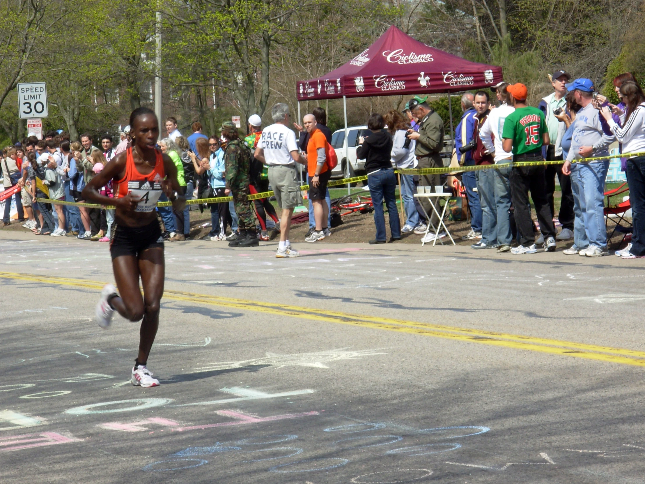 a woman is running down a street with other people watching