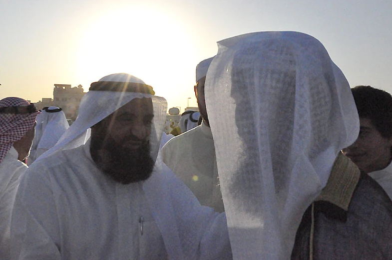 men in traditional arabian clothing are walking near each other