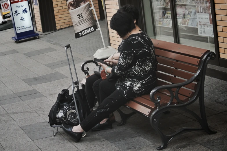 a person sitting on a bench next to a bag