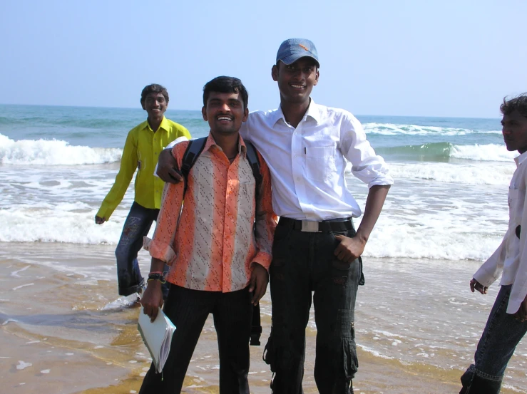 three men standing in the water on the beach with a woman and child