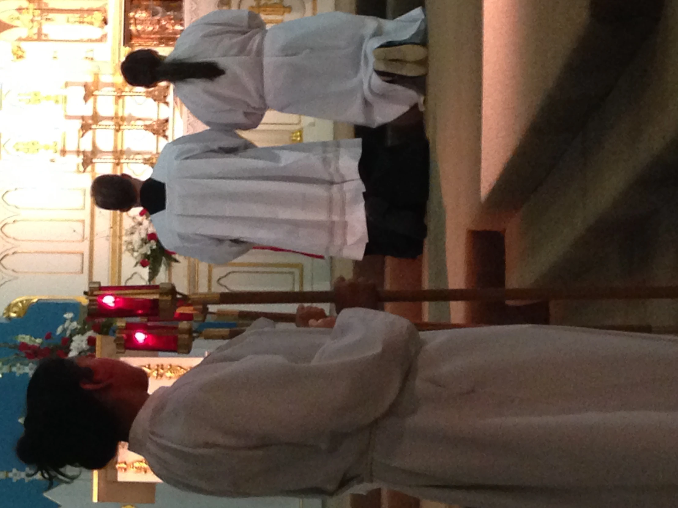 priest and two girls praying in a small church