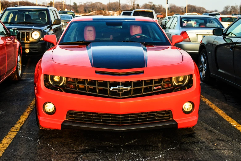 the people are looking at the orange muscle car