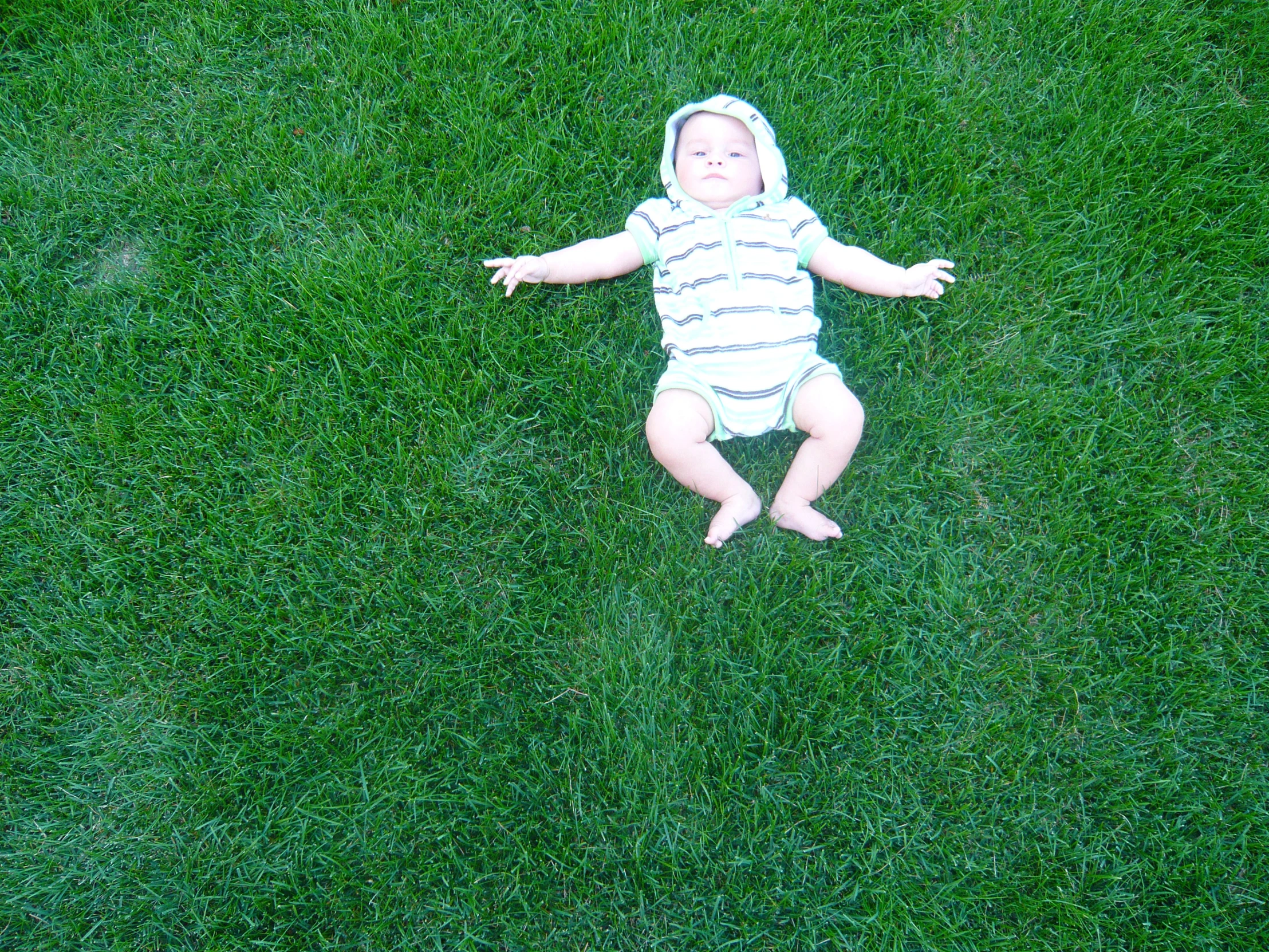 a baby is laying on a field and waving