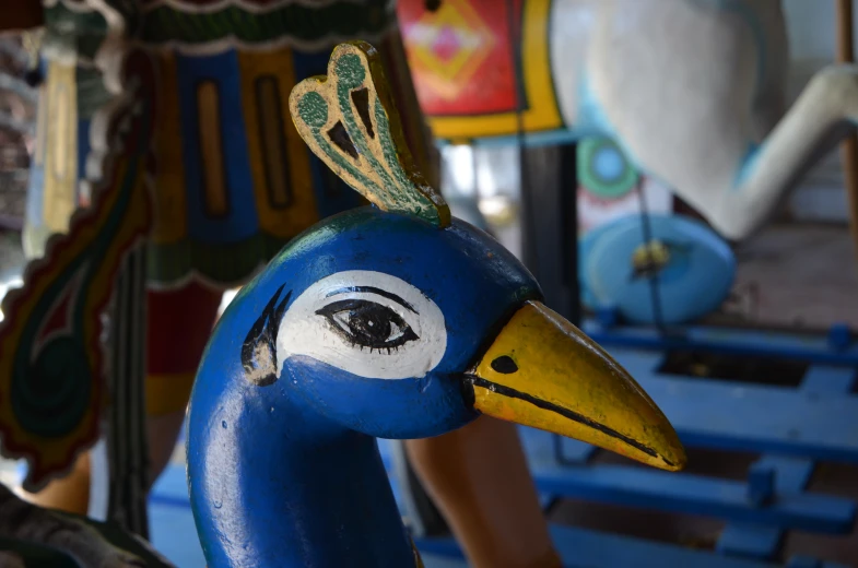 two ceramic sculptures of peacocks in front of a carousel