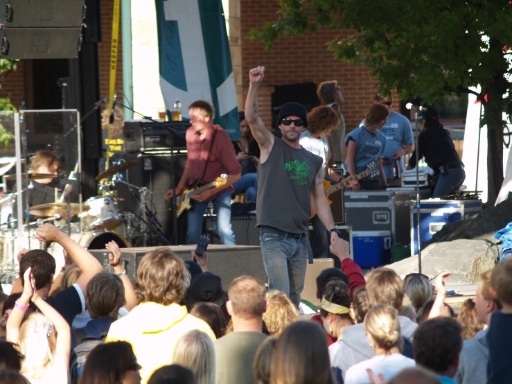 group of people at outdoor concert with one band on stage