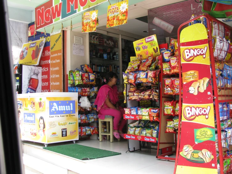 a woman sitting outside of a shop talking on her cell phone