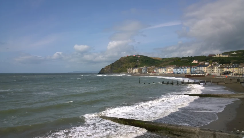 a beach with waves crashing on the shore and a small island in the background