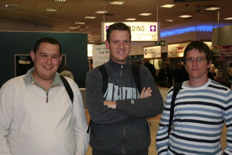 three men standing next to each other at an airport