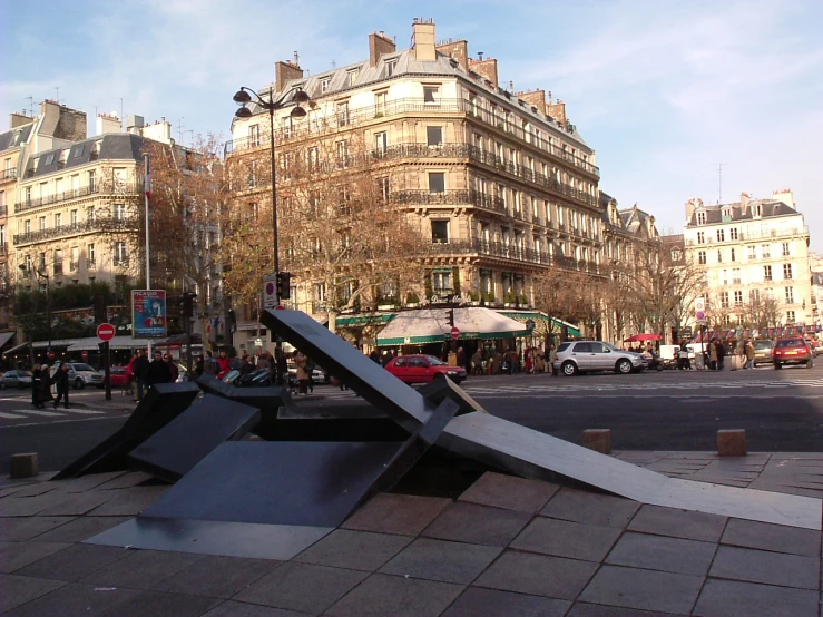 large metal object outside of a busy city plaza