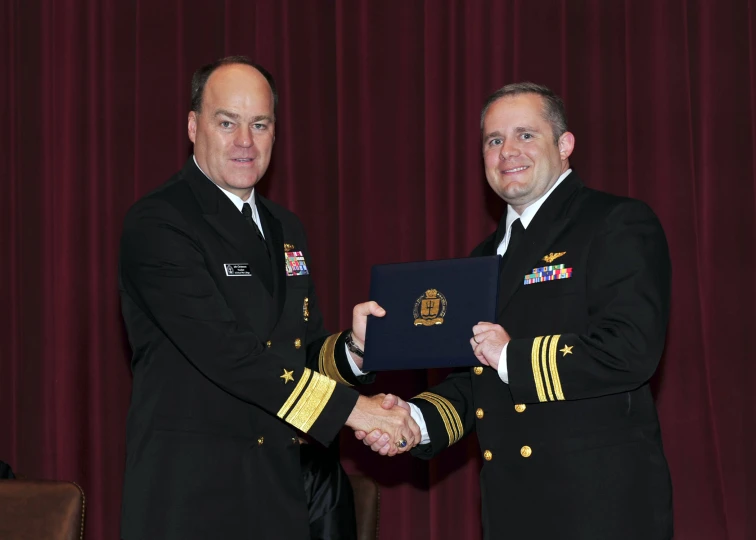 two military men are shaking hands and posing for a picture