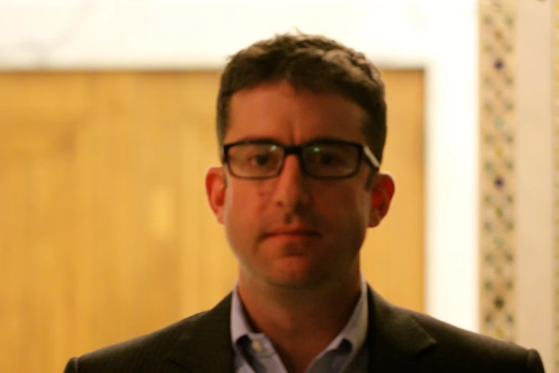 a man standing in front of a window wearing glasses