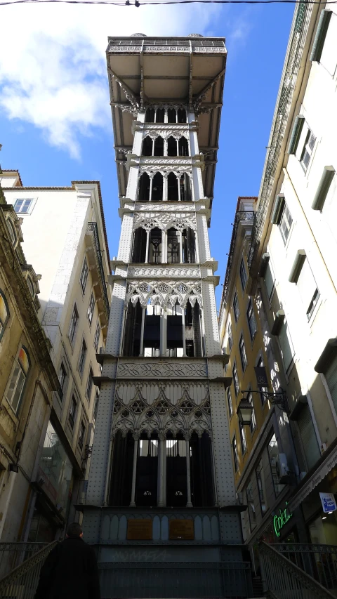 a tall building with windows above another building with other buildings in the background