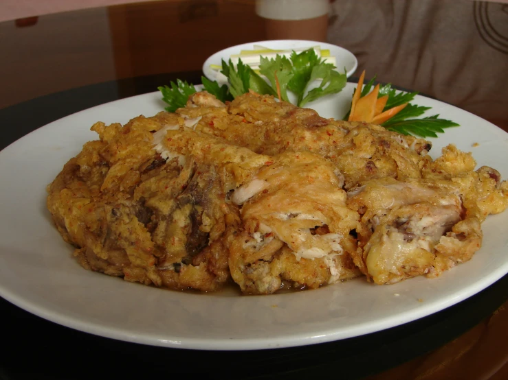 a white plate topped with fried food next to a small bowl